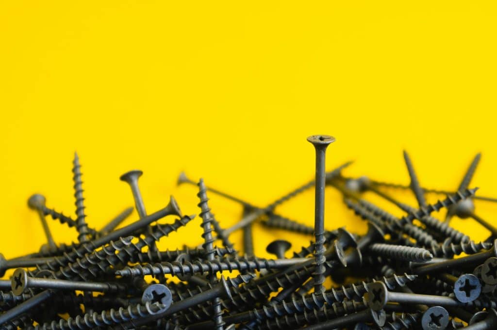 Gray metal screws on yellow background